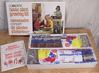 Opened kit box with seed packets, soil pellets, and trays visible in plastic packaging.