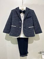 Front view of full baby suit set hanging, showing navy pinstripe blazer, white shirt, bow tie, and pants.