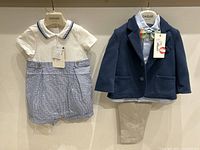 Full view of both outfits hanging side by side showing details and tags.