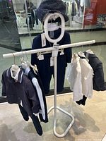 White metal children's clothing rack with black and white children's clothes hanging on it, showing its use and size.