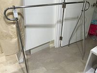 Front view of chrome metal clothing rack with tubular frame and horizontal crossbar for hanging clothes.