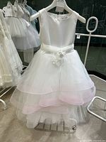Full front view of the white girl’s formal dress with sheer multi-layered skirt and pink edging
