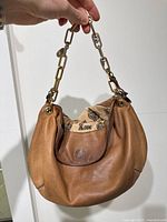 Front view of light brown leather Juicy Couture purse with chain handle and visible interior lining print.