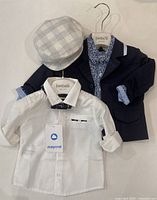 Full outfit including navy blazer, white shirt with tags, and gray checkered hat on hanger.