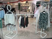 Photo showing the full clothing rack with clothing hanging and mannequins on each side in a store environment.