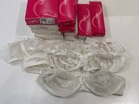 Photo of multiple bras laid flat showing lace and embroidered delicate details, some bras are off-white with aging wear