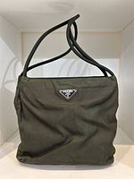 Front view of khaki nylon purse with Prada triangular logo plaque