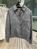 Front view of dusty blue vintage Armani Jeans jacket displaying button closure and pockets