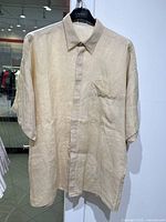 Front view of vintage cream short sleeve linen shirt with chest pocket and button front showing fabric texture and wear