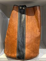 Front view of the vintage leather hobo bag showing cognac colored body and black vertical strip embossed with M. Rossetti.