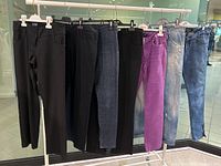 Full lot of seven women's trousers on a rack, showing colors and styles