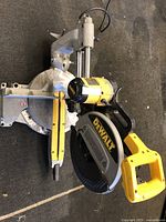 Overhead angled view of entire saw showing handle, blade guard, base, and rail on black carpet