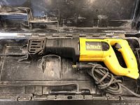 DeWalt DW303M reciprocating saw lying in its plastic carrying case, showing the entire saw with cord and blade mount.