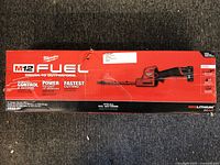 Front box view showing Milwaukee M12 FUEL branding, cordless hedge trimmer image, and product highlights.