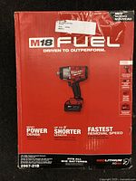 Front of sealed red cardboard box showing Milwaukee M18 Fuel logo and illustration of impact wrench