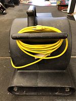 Front view showing yellow power cord wound around the handle on top of the black plastic blower housing.