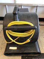 Front view of black Powr-Flite air mover with yellow cord wrapped around handle.
