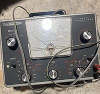 Front view of Heathkit Audio Generator Model IG-72 showing analog meter, control knobs for multiplier, frequency, output levels, power switch, and connected cables.