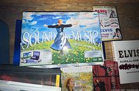 Photo showing The Sound of Music DVD set along with Elvis and Anne of Green Gables DVDs and anatomy book to right