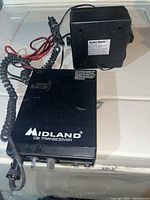 Midland CB Transceiver rectangular black unit with cables and Radio Shack power adapter placed on a surface.