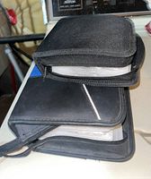 Two black zippered binders stacked together on a surface.