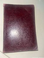 Front cover of the vintage hardcover book with dark red textured leather binding.