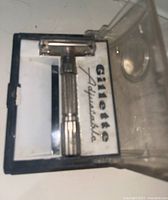 Top view of closed clear plastic case containing the Gillette adjustable safety razor with printed branding inside the case