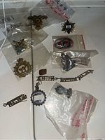 Top-view image showing assortment of military pins and badges in separate plastic bags with handwritten notes.