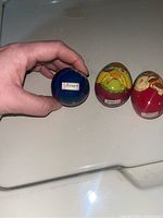 Three wooden Russian eggs arranged in a row, showing hang hooks and colorful painted designs.