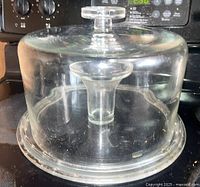 Glass dome lid covering the serving platter with central dip bowl, visible knob handle on top.