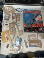 Photo showing assorted postage stamps attached to envelopes and strips of brown paper with the book 'Frank R Paul, Father of Science Fiction Art' in the background.