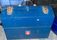 Exterior view of large blue steel toolbox with metal latches and handle, showing wear and scratches