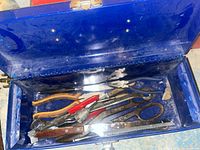 Photo of open blue Rona toolbox showing assorted hand tools inside including pliers, scissors, cutters, torch head, and small precision tools.