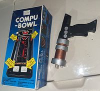 Photo of Sears Compu-Bowl handheld electronic bowling game with original box and USS Enterprise Phaser toy gun on a white surface