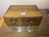 Front view of the oak index file with two drawers and metal handles on a wooden surface.