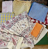 Multiple assorted fabric pieces laid out, showing various colors and patterns such as paisley, floral, and checks.