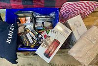 Box containing a folded black Harley Davidson sweater, various boxes including one labeled Canyon Dreams decorative lamp, candle holders in packaging, and other boxes of mixed items.