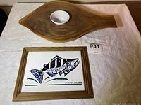 Two items displayed on a white quilted surface: the wood serving platter with attached ceramic bowl and the framed painted tile trivet featuring a Chinook Salmon.