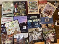 Top-down view of 14 coffee table books arranged in rows showing covers with cottage, garden, seaside and country themes