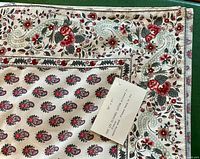 Close-up of floral and paisley pattern on cotton fabric with care label attached.