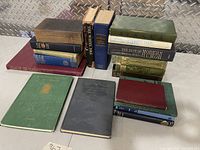 Wide shot showing all 18 vintage books in three groups on a table against a metal background.