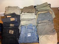 Photo showing folded assorted men's jeans and cargo pants of various colors arranged on a flat surface.