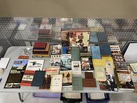 Overview of set of approx. 40 military-related books spread on a table, showing various titles and historical themes.