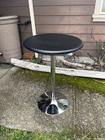 Full view of the adjustable pub style black round table with chrome pedestal base.