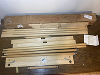 Wooden quilt frame components laid out on floor next to original box from Sears Chicago with label and storage wear.