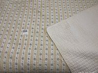 Quilt laid out flat on a king sized bed showing overall pattern and condition including small stain near corner.