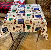 Nautical themed tablecloth displayed on table showing maritime design with flags, anchors, and ropes.