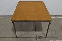 Front view of the vintage collapsible card table showing the brown rectangular top and metal legs.