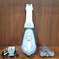 Front view of the hand vacuum with accessories showing the charging base and clear plastic attachment