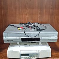 Stacked Toshiba SD-V394 combo DVD/VCR on top of Sony ICF-CD513 under cabinet clock radio with CD player showing front